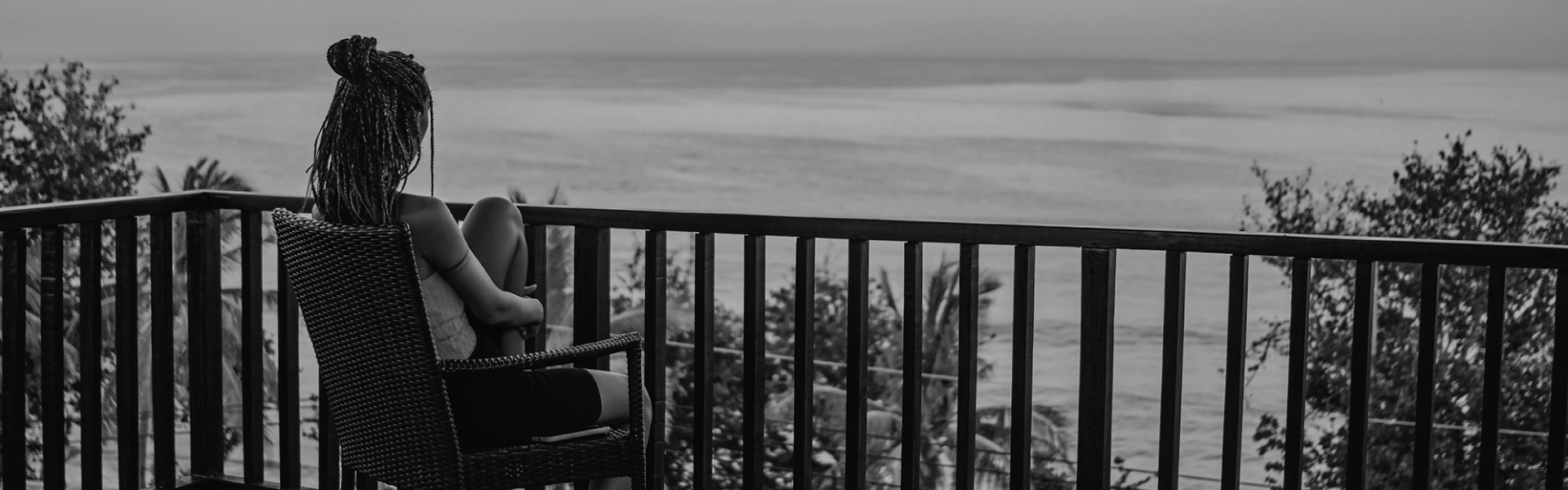 mujer sentada en su silla mirando hacia el mar desde un balcon